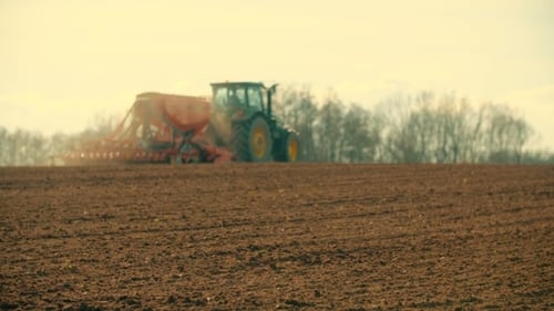 Traktor pflügt Feld bei Sonnenuntergang
