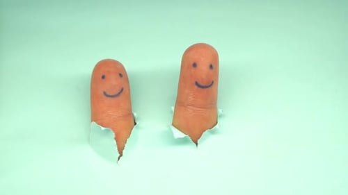 Human Fingers with Smiling Faces Tearing Blue Paper and Pretending