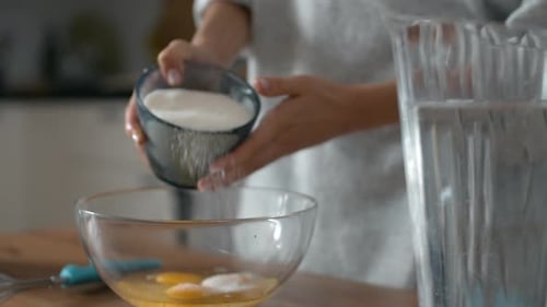 Adding Sugar to Bowl of Eggs in Kitchen