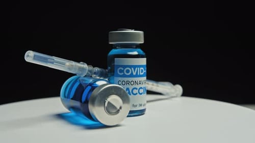 COVID-19 Vaccine Vials with Syringe on White Surface