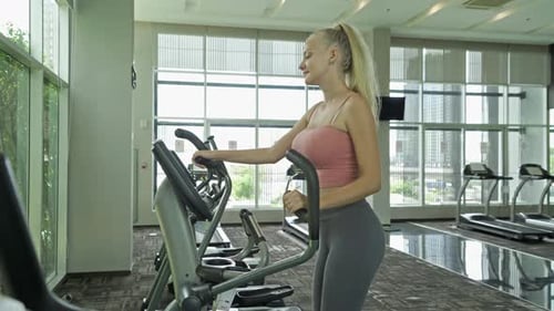 Woman Exercising on Elliptical Machine in Gym