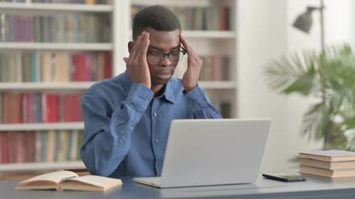 Young Adult with a Headache Typing on Laptop