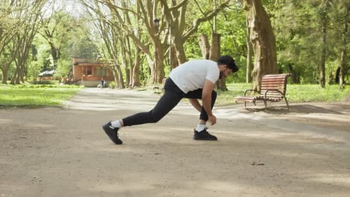 Man Stretching Leg in the Park on Sunny Day