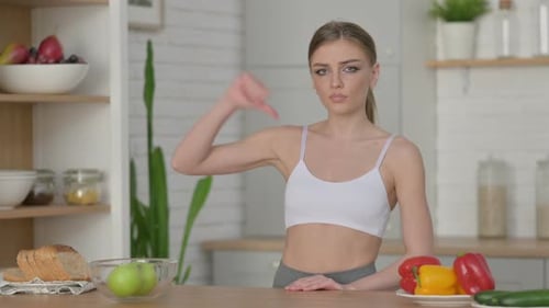 Sporty Woman Showing Thumbs Down While Standing in Kitchen