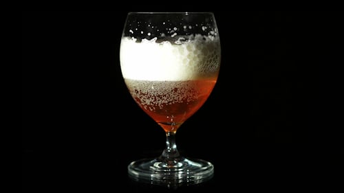 Effervescent Beer with Thick Foam Settles in Glass