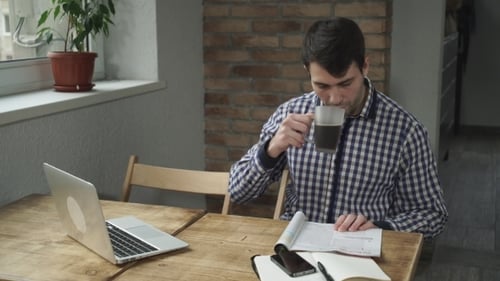 Im Café Der Mann, der an einem Tisch sitzt, eine Zeitschrift liest und Kaffee trinkt.