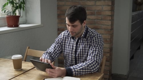 Young Adult Using Tablet at Wooden Table