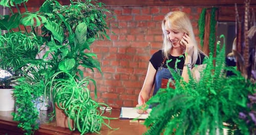 Woman on Phone Taking Notes in Plant Store