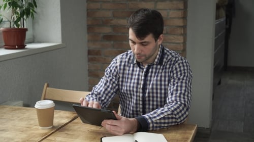 Young Adult Using Tablet at Table Indoors