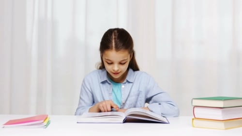 Happy School Girl Reading Book Or Textbook At Home