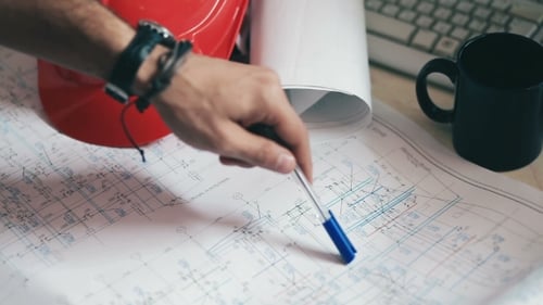 Hand des Ingenieurs zeigt Details auf Blaupausen an