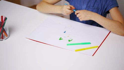 Child Draws with Markers at White Table