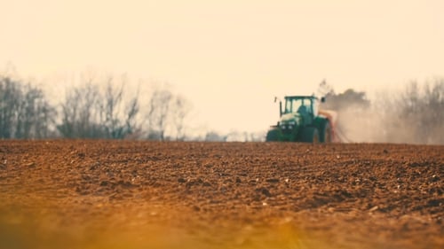 Traktor pflügt Feld bei Sonnenuntergang
