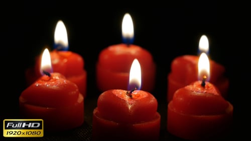 Heart Shaped Candles Burning Against Black Background