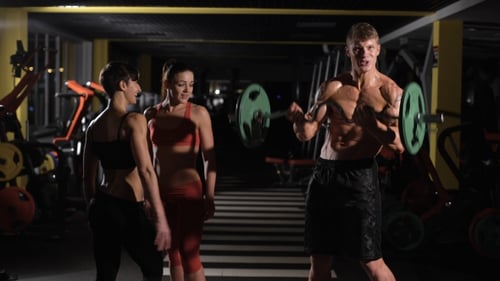 Man Lifts Barbell with Encouragement in a Gym