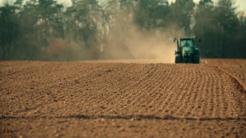 Traktor pflügt Feld bei Sonnenuntergang