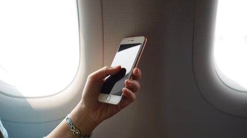 Hand Holds Mobile Phone on Airplane