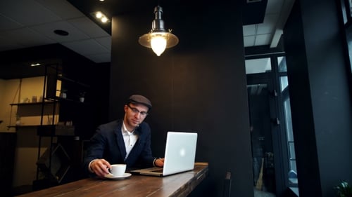 Young Man Drinking Coffee On The Street While Using Tablet Computer