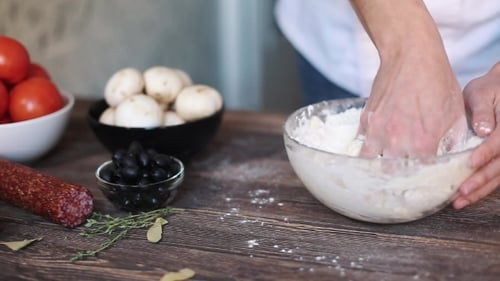 Hands Kneading Dough for Pizza With Ingredients