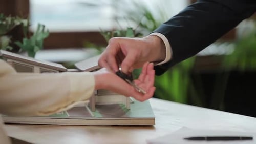 Business, Real Estate, Deal and People Concept - Man Giving House Keys To Woman at Office.