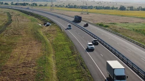 Aerial View of a Busy Highway with Cars and Trucks Among Fields and Hills