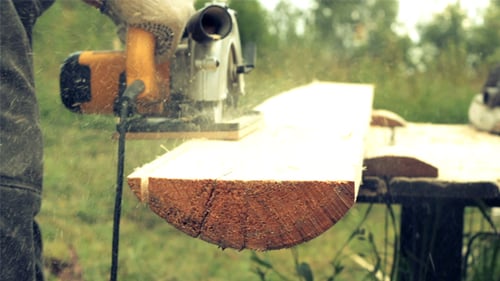 Worker Cutting Wooden Floor by Electric Saw
