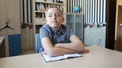 Pensive Boy at Desk with Book in Room