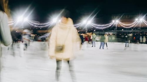People Ice Skating on Rink at Night