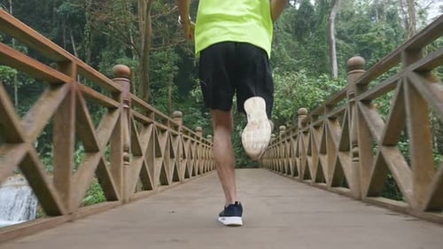 Man Running on Bridge in Tropical Forest