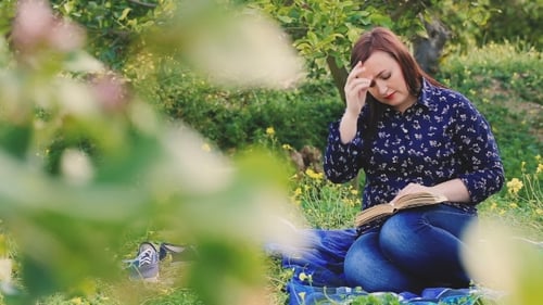 Attractive Woman Reading Book In Park And Looking At Camera.