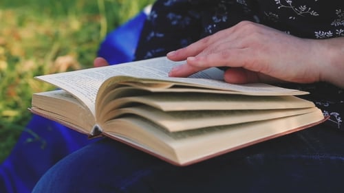 Woman's Hand Reading a Book In The Park.