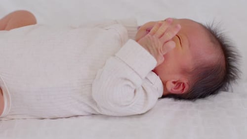 Top view happy newborn baby lying sleeps on a white blanket comfortable