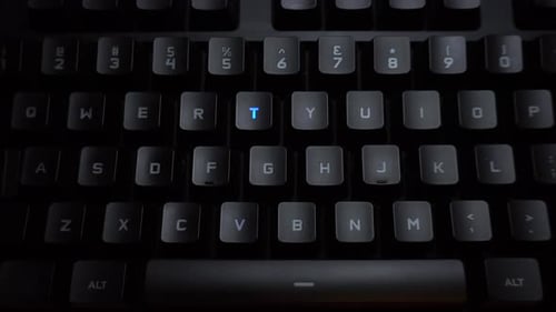 Das Wort TV wird auf einer leuchtenden Computertastatur eingegeben. Tastatur mit schwarzer Hintergrundbeleuchtung und Buchstaben.
Die