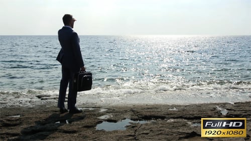 Man in Suit Stands at Ocean's Edge