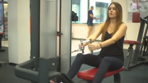 Young Woman Works Out on Row Machine in Gym