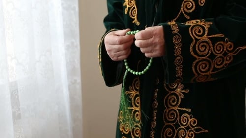 Hands Holding Beaded Prayer Beads Near Window