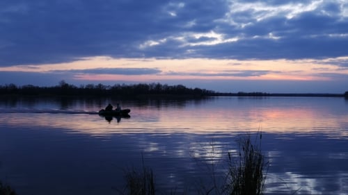 Motorboat Cruising on Lake at Sunset