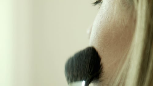 Woman Applying Makeup to Cheek with Brush