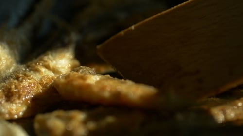 Fish Cooking in Pan with Wooden Spatula