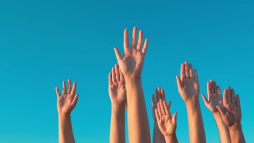 Mains levées contre le ciel bleu