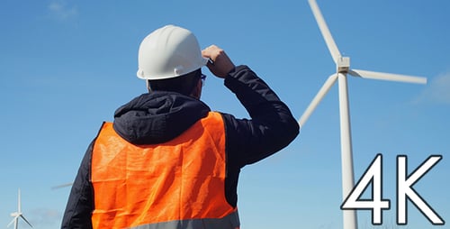 Engineer Inspecting Wind Turbines on a Sunny Day