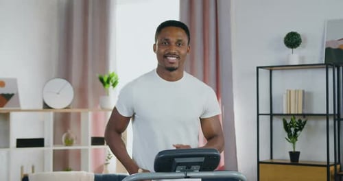 Young Adult Male Jogging on Treadmill at Home