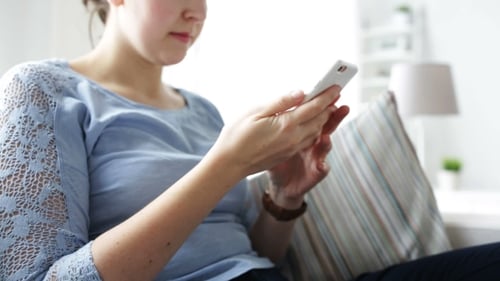 Woman Using Smartphone Relaxing on Couch Indoors