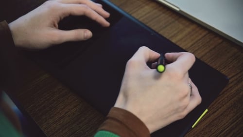 Hands Use Graphics Tablet on Wooden Desk