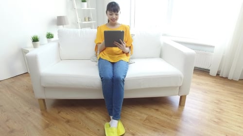 Woman Using Tablet on Couch at Home