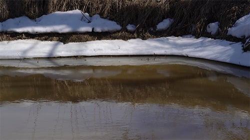 Stream flowing in winter with snow covered banks