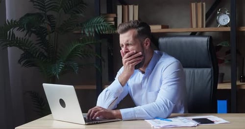 Tired Man Falls Asleep at Desk in Office
