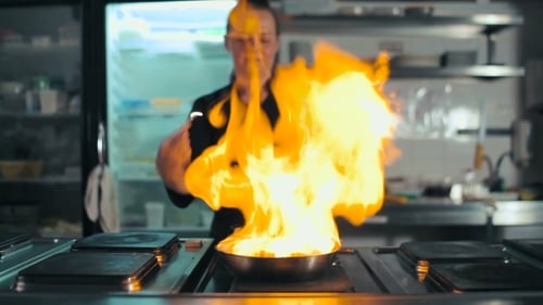 Koch macht Flambe mit Wurst