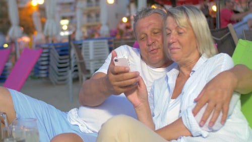 Loving Couple Using Phone on Beach at Night
