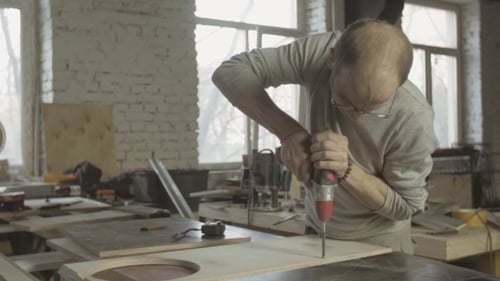 Man Drilling Wood with Power Drill in Workshop